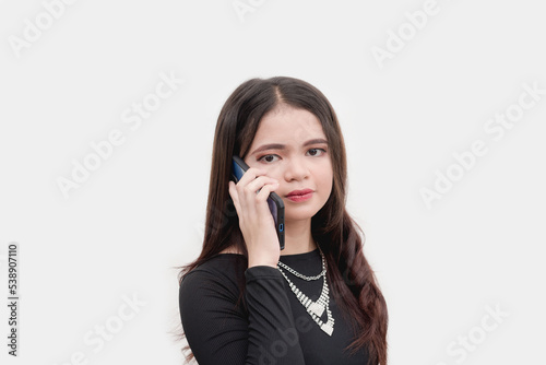 A female teenager puts on a serious look as she heard the bad news while speaking on the phone with her friend. Studio shot isolated on a white background.