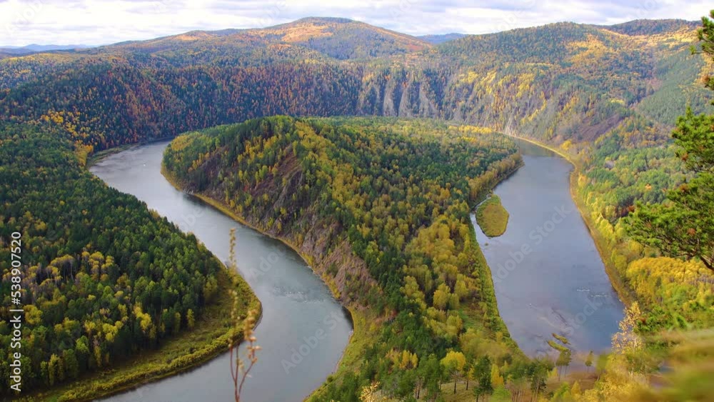 Windy autumn morning over the winding river. Moving clouds in the sky. Colorful autumn landscape with loop on meandering river among mountains in Siberia.