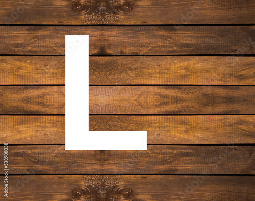 L capital letter of alphabet in white hole on wood background