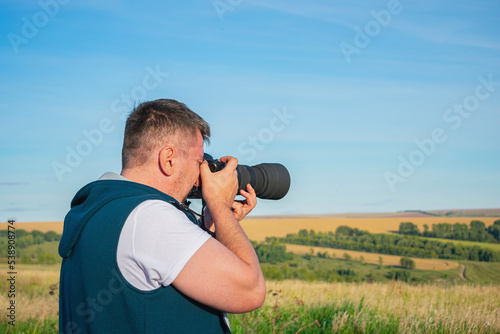 A professional photographer captures a rural landscape with an expensive camera