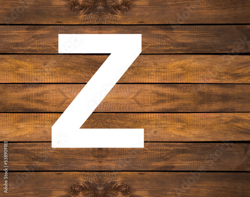 Z capital letter of alphabet in white hole on wood background