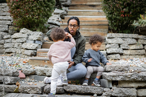 Black mom helping biracial son up the stairs in backyard