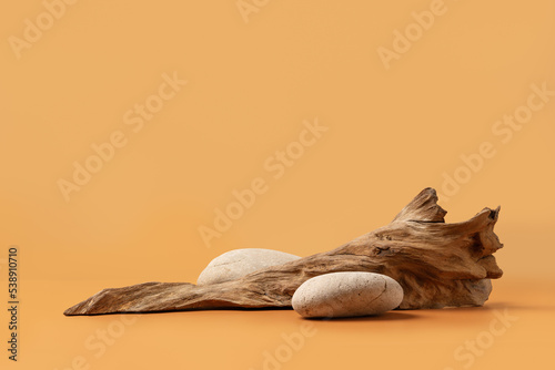 Fototapeta Naklejka Na Ścianę i Meble -  Mockup stage for advertising made with stones and weathered snag on a sandy background with copy space. Natural pedestal for cosmetic product presentation or package advertisement.
