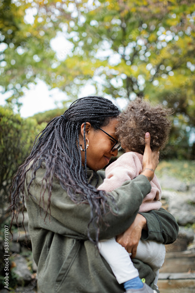 Black mother hugging toddler boy and smiling in fall Black mother hugging toddler boy and smiling in fall