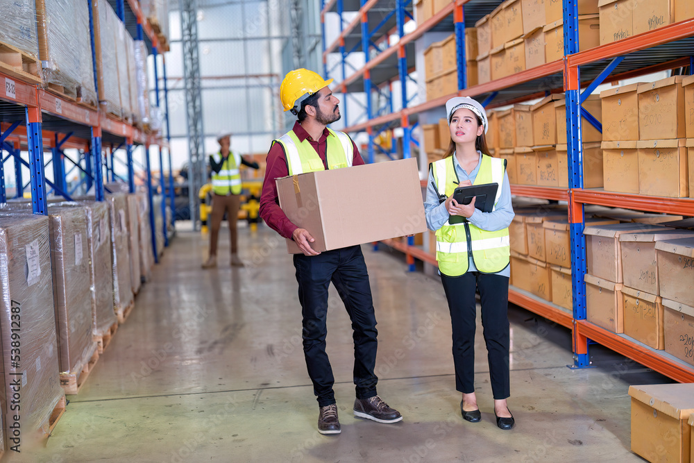 Foto de Warehouse worker hold the carton box walk along the steel