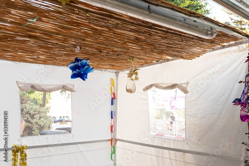 Jewish festival of Sukkot in Israel. Traditional sukkah with handmade decorations near the building on the street.  photo