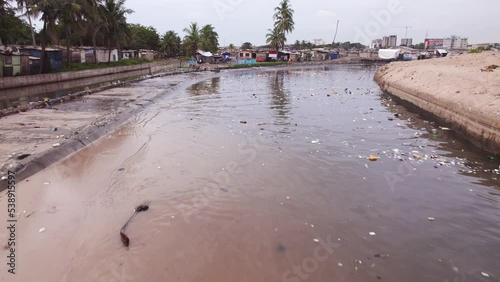 Sweeping Aerial of Polluted Lagoon by Slum Settlement in Ghana Africa photo