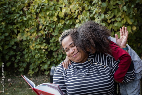 Young Black boy hugging his aunt in the park while smiling