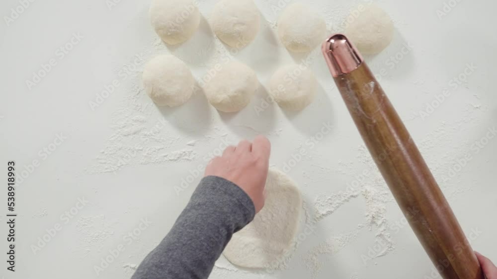 Flat lay. Rolling bread dough with a french rolling pin to make homemade flatbread.