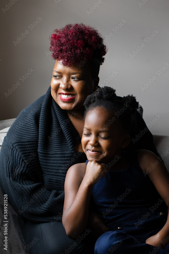 Obraz premium African American mother and daughter smiling and looking out window