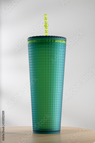 Green plastic tumbler size 22 ounces on a wooden table