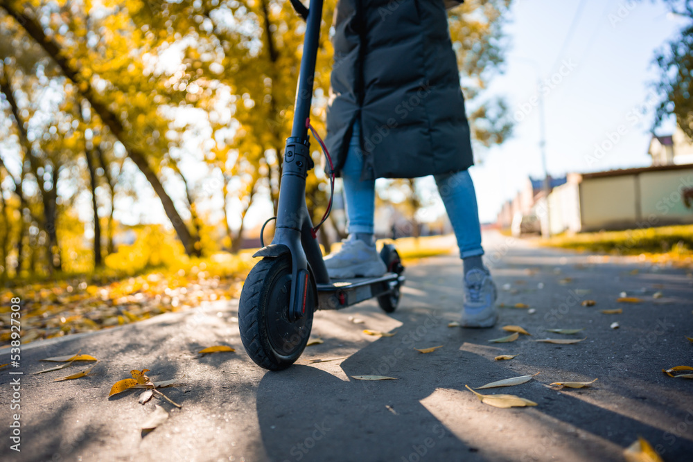 Obraz premium young girl with long coat riding an electric scooter
