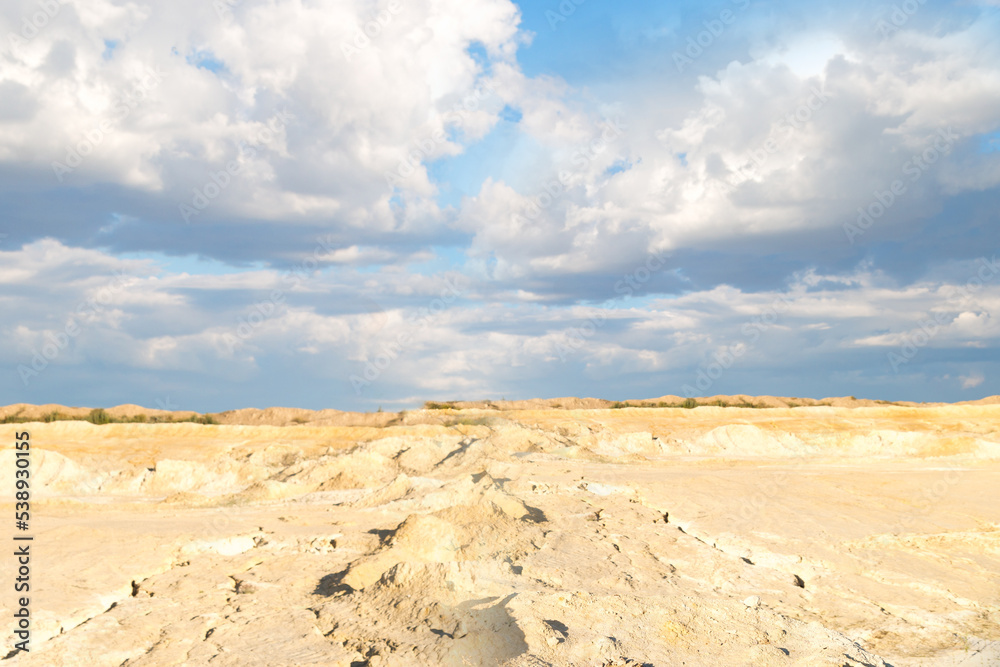 Open dry terrain with a rocky surface with blue sky and beautiful clouds.