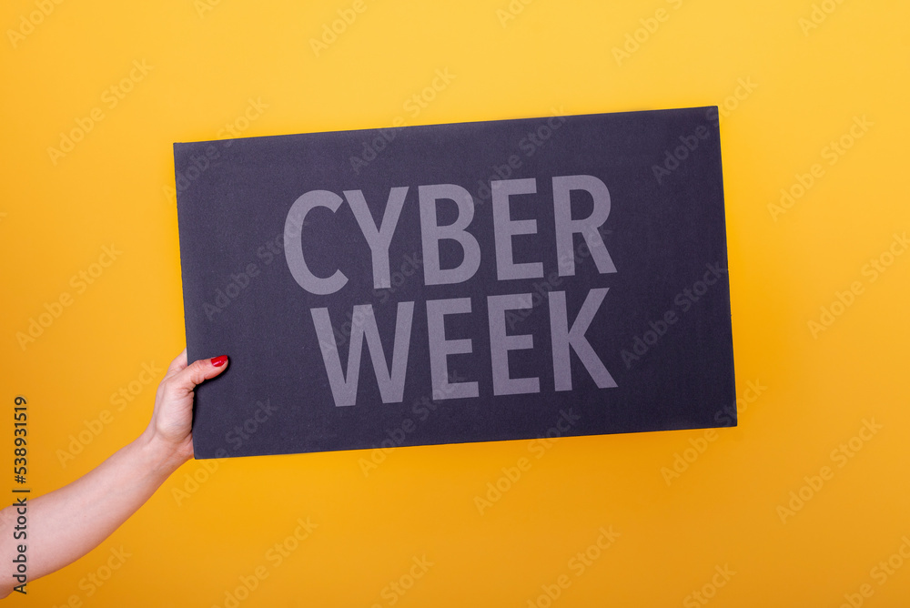 Female hand holding a cyber week poster. Studio shot. Commercial concept. - obrazy, fototapety, plakaty 