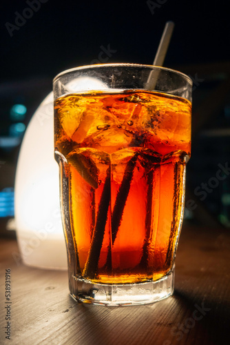 White rum and coke with ice in a glass with a straw