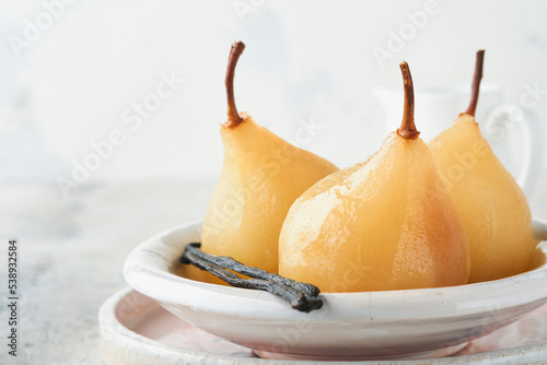 Pears. Poached pears in syrup. Traditional dessert sliced server in a white plate with leaves and at home on a light background. Delicious dessert for holiday.
