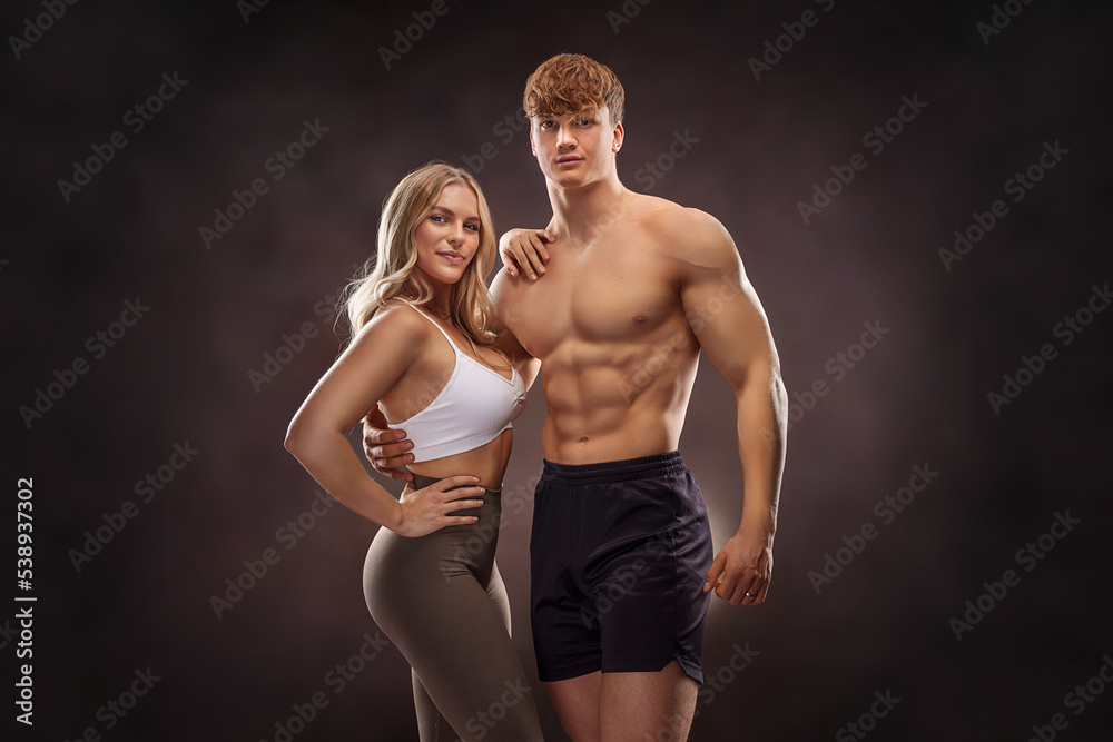 Portrait of young sporty people guy and girl 20s in basic clothing posing together at camera with happy look, isolated over concrete gray wall indoor Portrait of young sporty people guy and girl 20s in basic clothing posing together at camera with happy look, isolated over concrete gray wall indoor