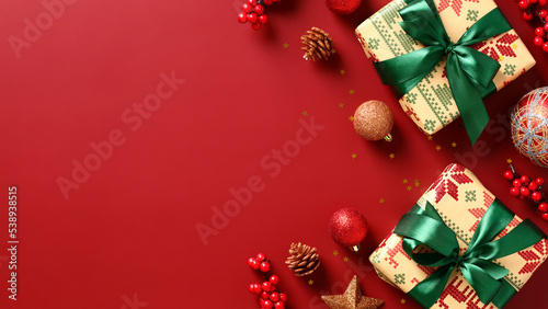 Christmas banner design. Vintage gift boxes with green ribbon, baubles, branches of red berries on red background. Xmas greeting card, New Year header template.