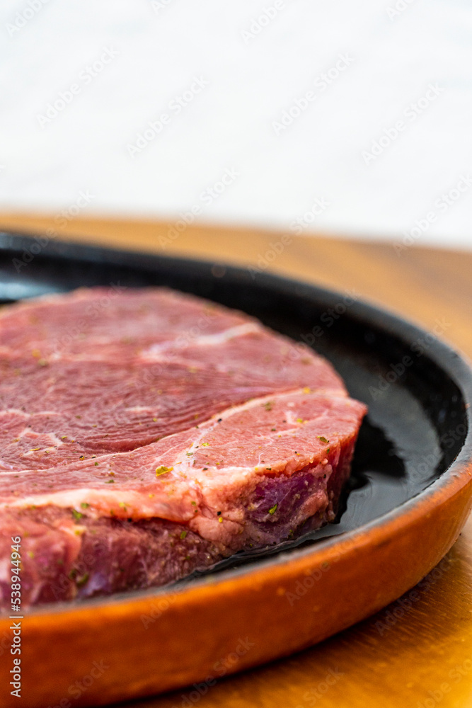 raw meat served in a black earthenware dish on a wooden table, mexico raw meat served in a black earthenware dish on a wooden table, mexico