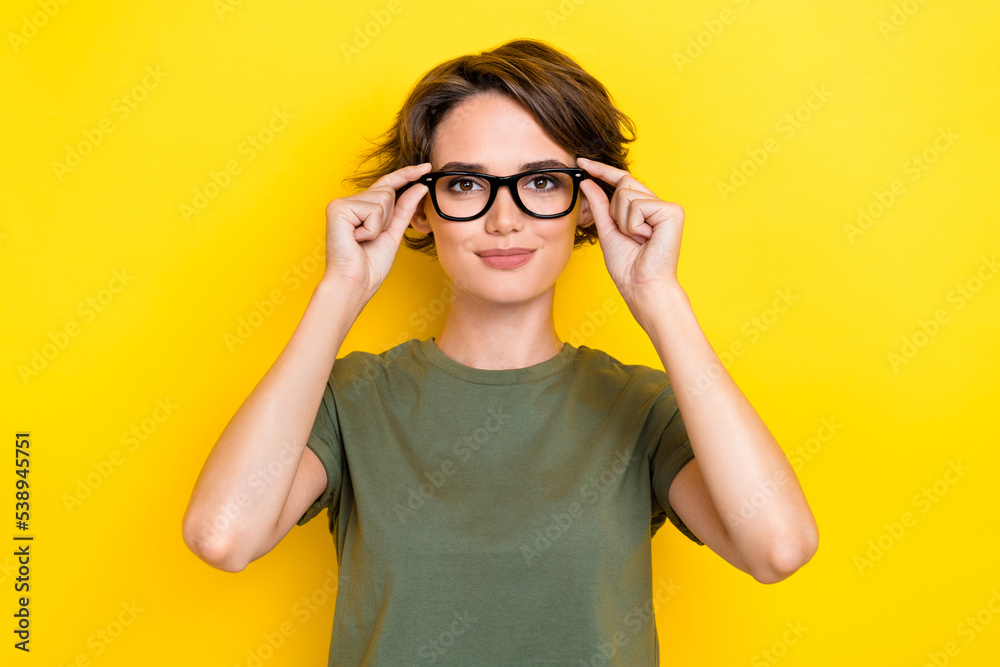 Portrait of gorgeous pretty nice woman with bob hairdo dressed khaki t-shirt hands touch glasses isolated on yellow color background Portrait of gorgeous pretty nice woman with bob hairdo dressed khaki t-shirt hands touch glasses isolated on yellow color background