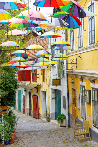 Canvas Print Colorful fun umbrellas hanging over the street in Szentendre with flowers