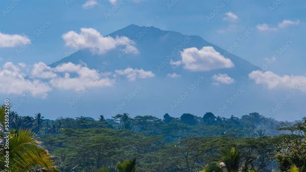Timelapse of clouds moving in blue sky on sunny day with a mountain on background. trees, tropical area