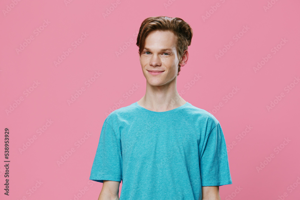 horizontal photo of a young man on a pink background in a blue t-shirt