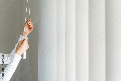 woman open white fabric vertical jalousie in room photo