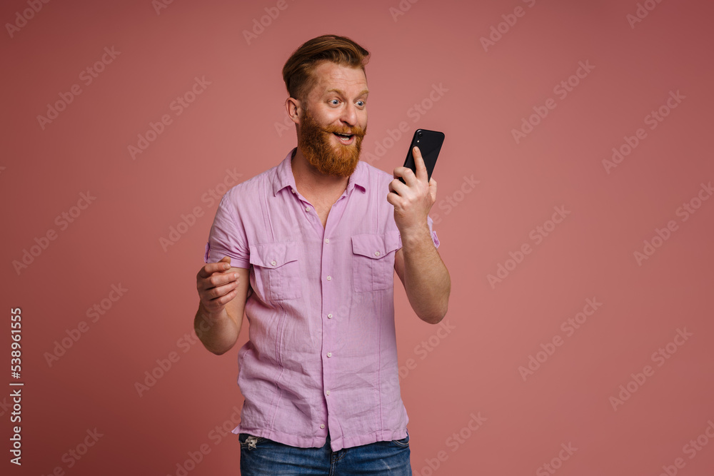 Ginger white man expressing surprise and using mobile phone Ginger white man expressing surprise and using mobile phone