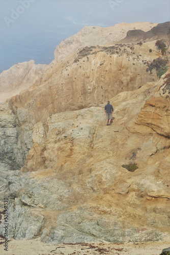 A man climbing a cliff at Bodega Head on the Sonoma Coast in California.