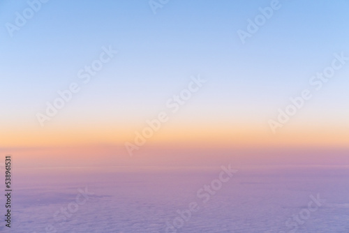 Aerial view of bright yellow sunset over pink purple dense clouds with blue sky overhead  top view from an airplane. Sky Gradient. Can be used as advertising background  overlay. Travel concept.