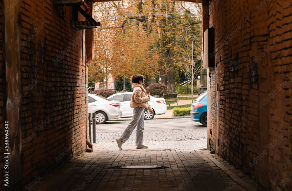 A woman walks along a city street, a view from the alley, a casual passer-by.