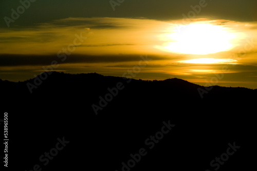 tramonto siluette montagna con sole e foschia di nuvole