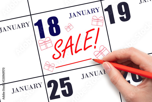 Hand writing text SALE and drawing gift boxes on calendar date January 18. Shopping Reminder