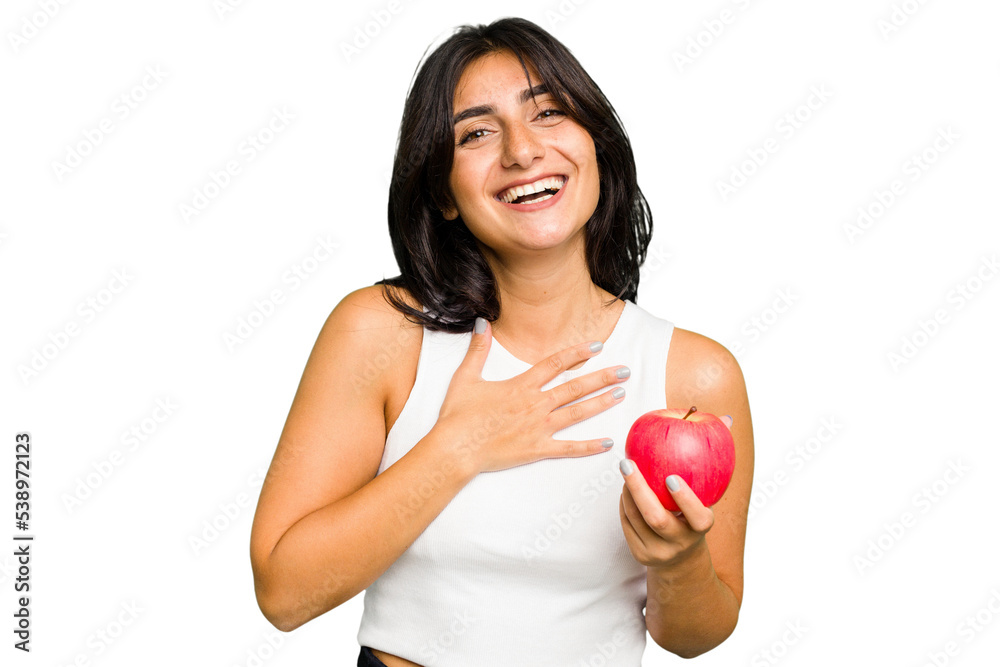 Young Indian woman holding an apple, healthy lifestyle, isolated laughs out loudly keeping hand on chest. Young Indian woman holding an apple, healthy lifestyle, isolated laughs out loudly keeping hand on chest.