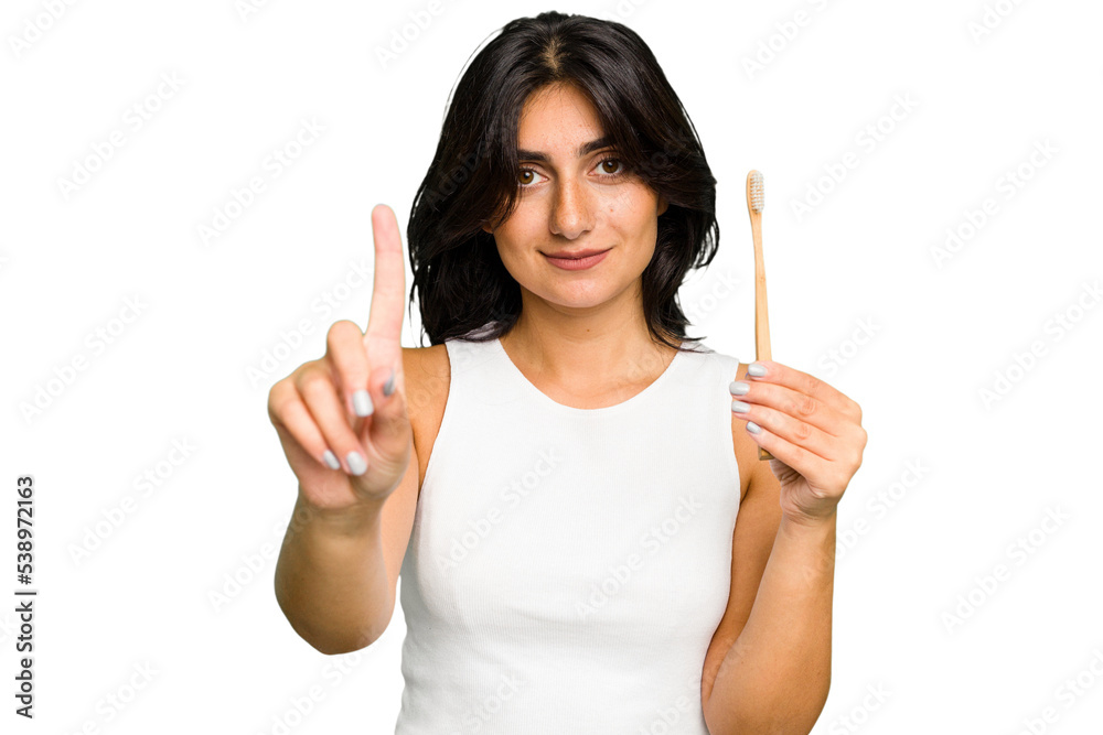 Young Indian woman holding a toothbrush isolated showing number one with finger. Young Indian woman holding a toothbrush isolated showing number one with finger.