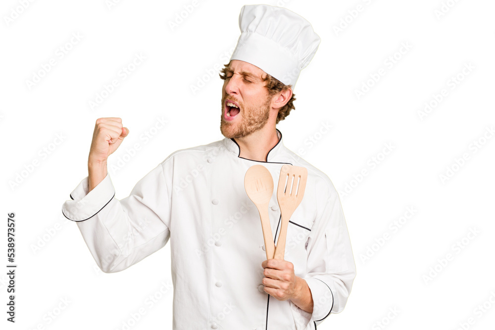 Young cook man isolated on white background raising fist after a victory, winner concept. Young cook man isolated on white background raising fist after a victory, winner concept.