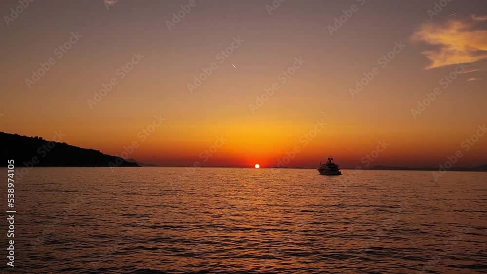 Sunset over ocean waves with mountains and a boat on the background. Tropic nobody. Mountain silhouette. Tropical golden sunset. Sun setting reflection on seascape. Calm waterscape. Sunset over ocean waves with mountains and a boat on the background. Tropic nobody. Mountain silhouette. Tropical golden sunset. Sun setting reflection on seascape. Calm waterscape.