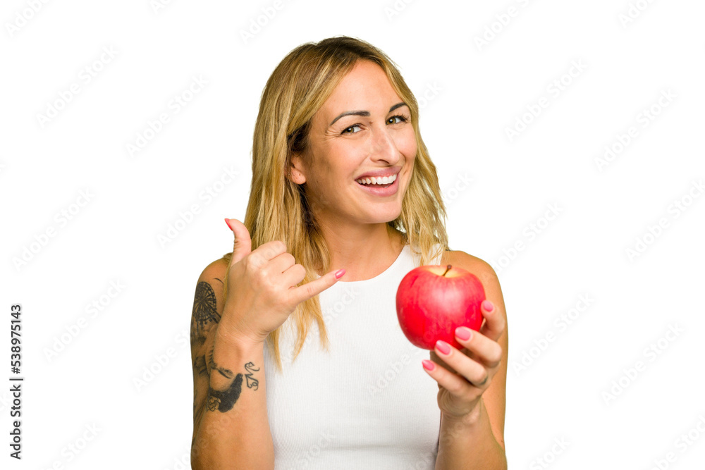 Young caucasian woman holding an apple isolated on green chroma background showing a mobile phone call gesture with fingers. Young caucasian woman holding an apple isolated on green chroma background showing a mobile phone call gesture with fingers.