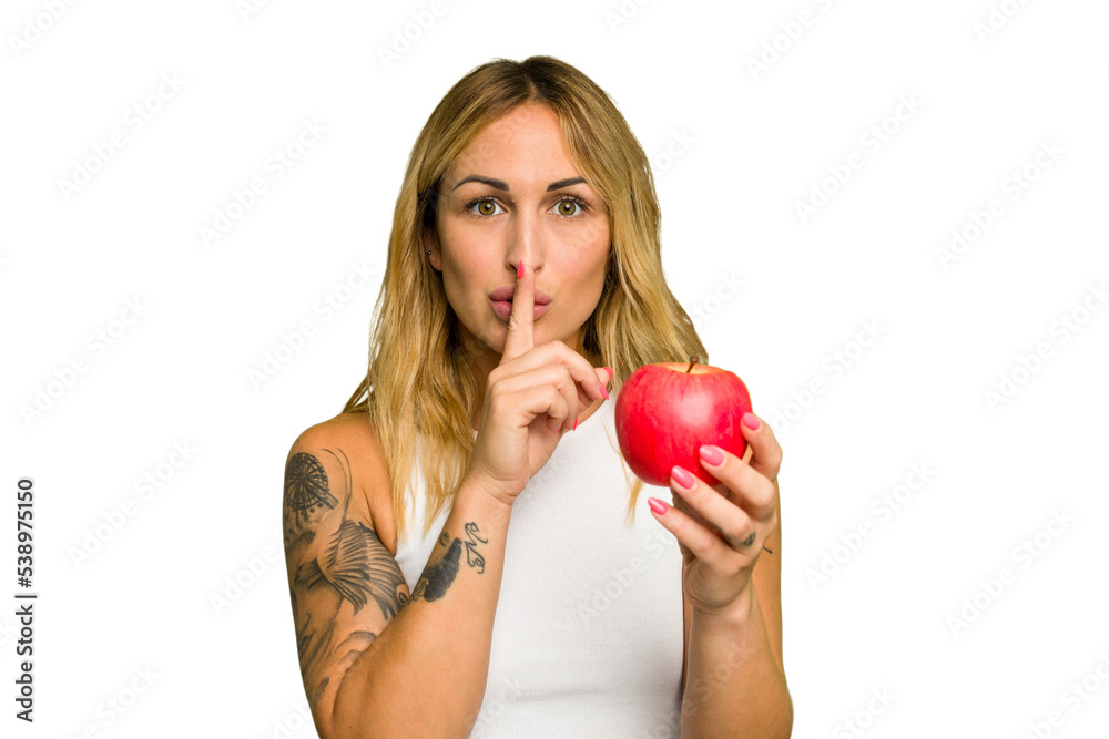 Young caucasian woman holding an apple isolated on green chroma background keeping a secret or asking for silence. Young caucasian woman holding an apple isolated on green chroma background keeping a secret or asking for silence.