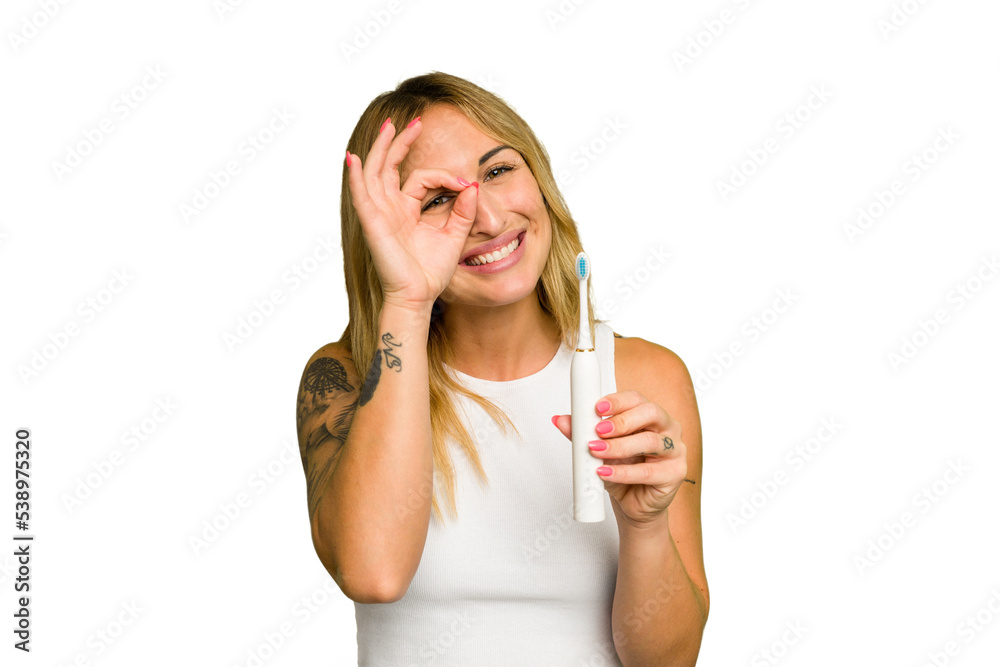 Young caucasian woman holding electric toothbrush isolated on green chroma background excited keeping ok gesture on eye. Young caucasian woman holding electric toothbrush isolated on green chroma background excited keeping ok gesture on eye.