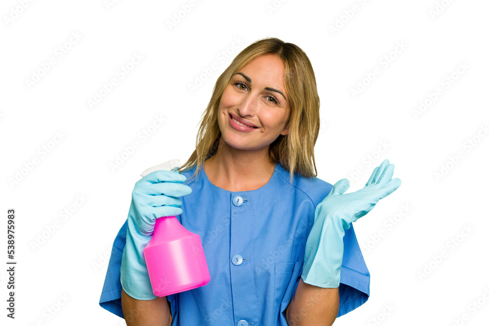 Young cleaner caucasian woman isolated green chroma background showing a copy space on a palm and holding another hand on waist. Young cleaner caucasian woman isolated green chroma background showing a copy space on a palm and holding another hand on waist.