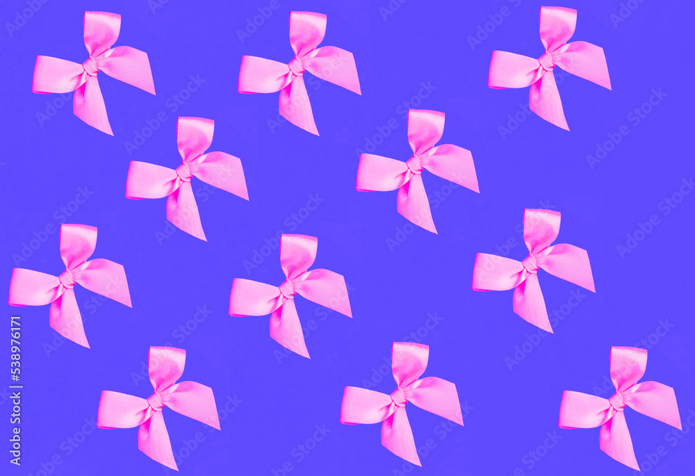 Holiday background. Pink bows on the purple background. Pattern. Flay lay. Holiday background. Pink bows on the purple background. Pattern. Flay lay.