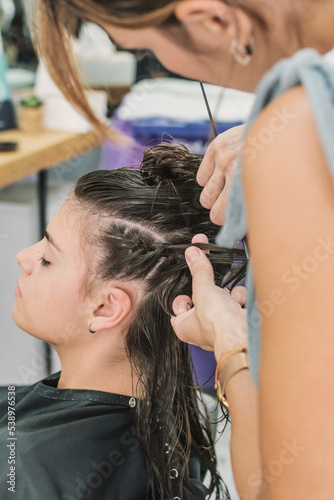 A Person Having A Weave Hair Extension Braided In An Urban Real-Life Salon. Woman At The Hairdresser. Female hairdresser while working.