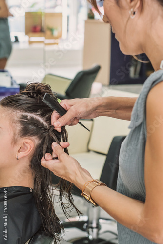 Young Woman With A Braided Hair Extension In A Beauty Salon, Real Life. Woman at the hairdresser. Hairdresser while working.