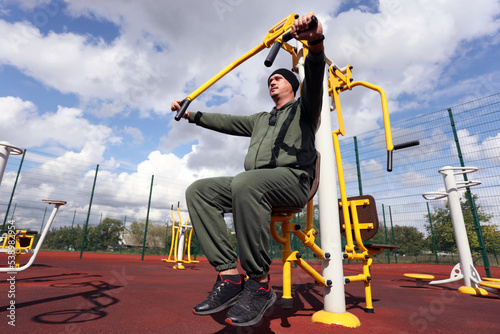 Man in city outdoor sports ground doing chest exercises