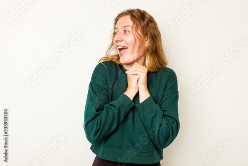 Young caucasian woman isolated on white background keeps hands under chin, is looking happily aside.