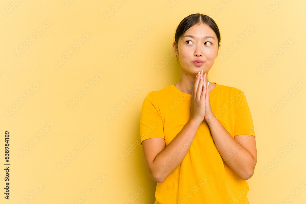 Young Asian woman isolated on yellow background making up plan in mind, setting up an idea.