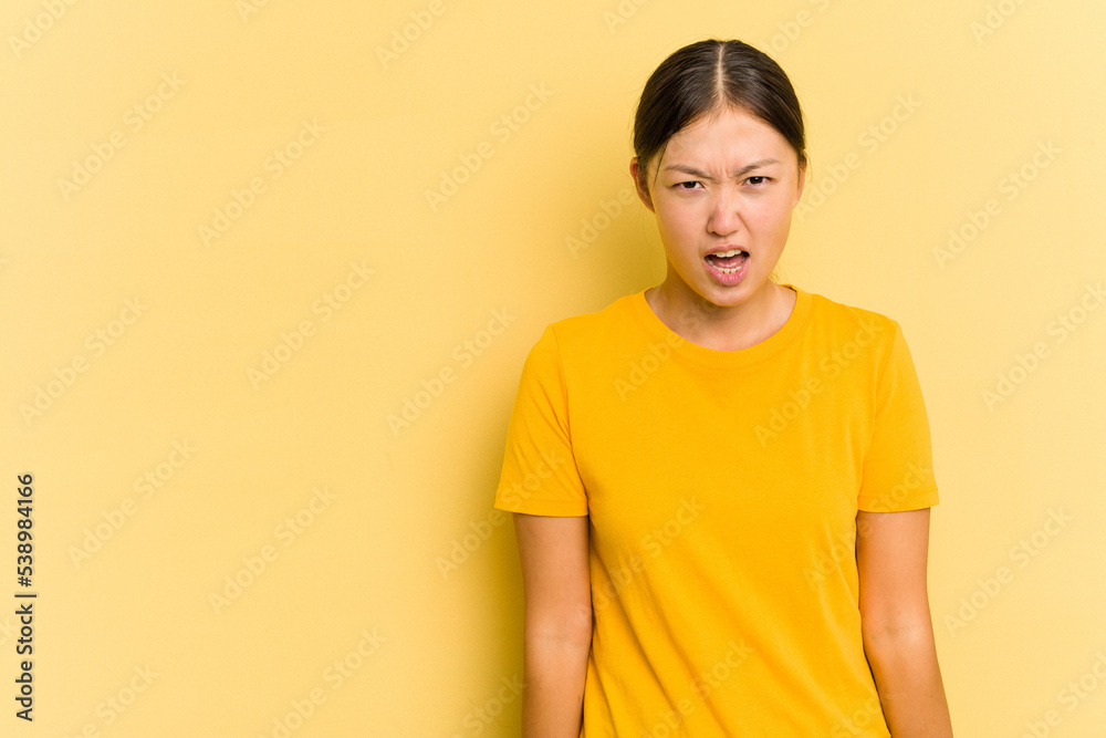 Young Asian woman isolated on yellow background shouting very angry, rage concept, frustrated. Young Asian woman isolated on yellow background shouting very angry, rage concept, frustrated.