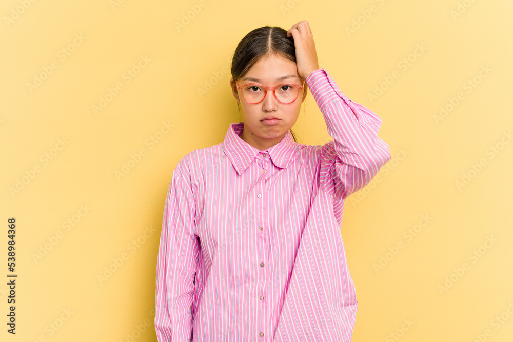 Fototapeta premium Young Asian woman isolated on yellow background tired and very sleepy keeping hand on head.